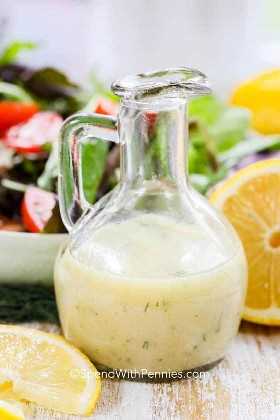 Aderezo de vinagreta de limón en una botella de vidrio con una ensalada fresca
