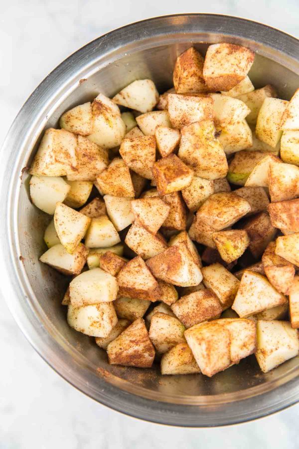 un bol plein de pommes hachées recouvertes de cannelle prêt à cuire dans un gâteau aux pommes juif