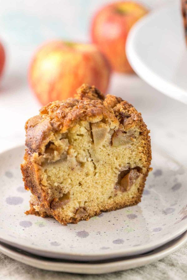 Vue latérale d'une tranche de gâteau aux pommes juif montrant les gros morceaux de pommes couvertes de cannelle et de miettes de gâteau fines