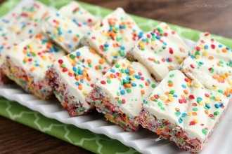 Piedras afrutadas, malvaviscos, chocolate blanco y chispas de confeti, se unen para hacer estas golosinas Rainbow Krispie. ¡Un postre fácil para el Día de San Patricio!