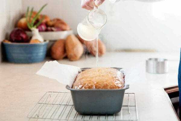 Lemon Glaze for Pound Cake - mujer vertiendo jarabe simple de limón sobre libra cake