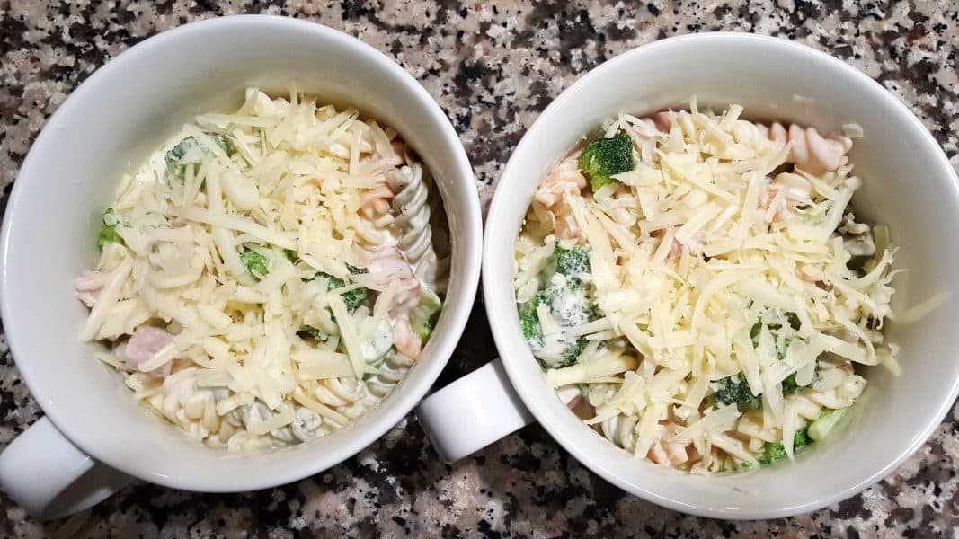 dos platos aptos para horno rellenos de jamón con queso, brócoli a la cazuela y cubiertos con queso rallado