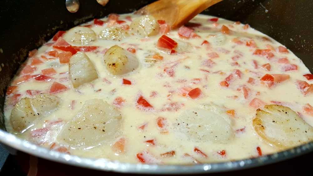 tocino, tomates y vieiras cocinando en una salsa cremosa en una sartén "srcset =" https://cdn1.zonacooks.com/wp-content/uploads/2017/11/Cheesy-Garlic-Bacon-Scallops-and-Linguine-Recipe -13.jpg 1000w, https://cdn1.zonacooks.com/wp-content/uploads/2017/11/Cheesy-Garlic-Bacon-Scallops-and-Linguine-Recipe-13-500x282.jpg 500w "tamaños =" (ancho máximo: 1000px) 100vw, 1000px