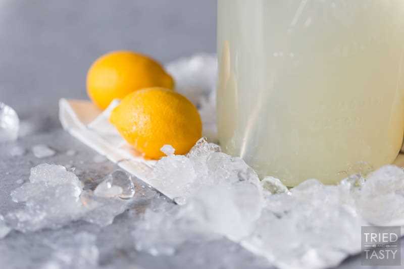 Ice on a table with two lemons & a jar of lemonade