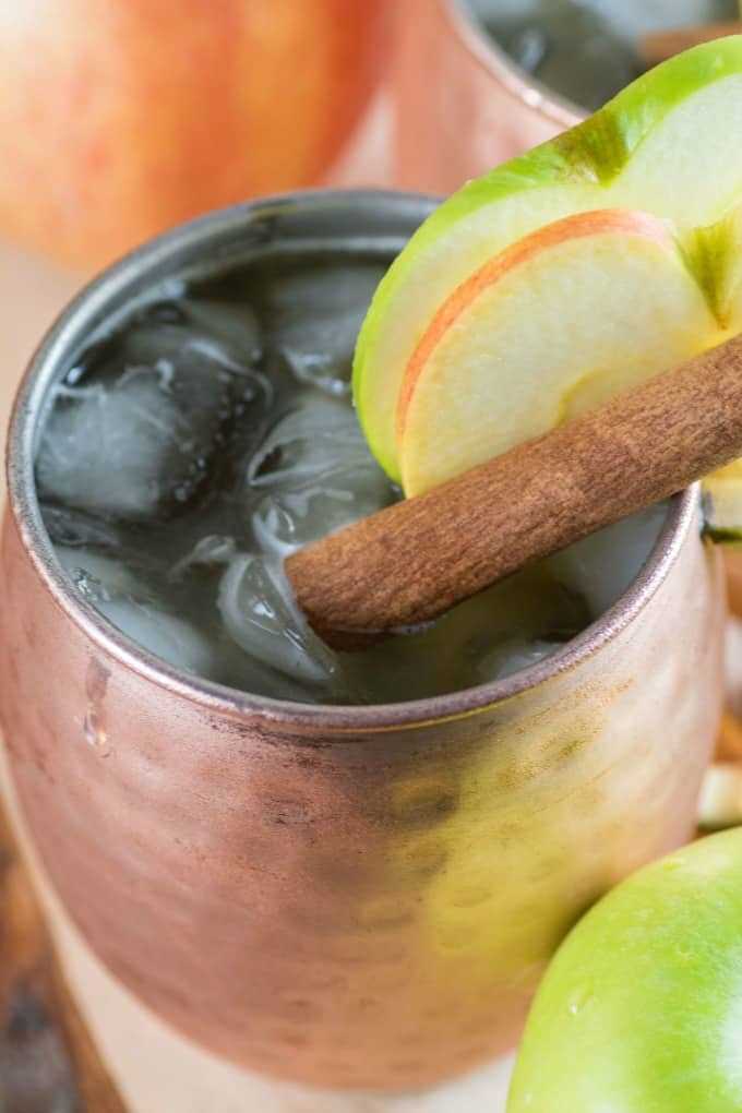 Cerca de una manzana Bourbon Moscow Mule en una taza de cobre con rodajas de manzana. 