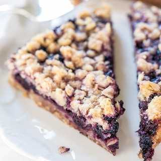 four blueberry bars with oatmeal crumble topping on white plate