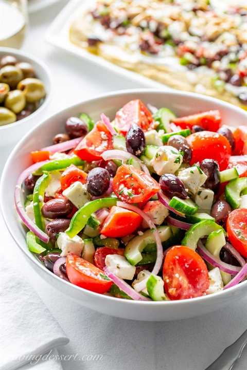 Тарелка греческого салата с помидорами, оливками, огурцом и сыром фета.