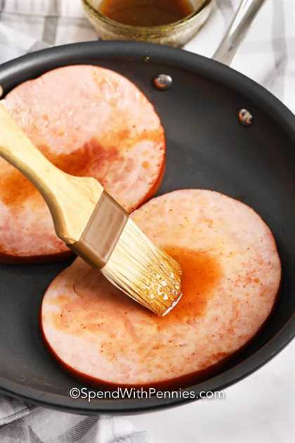 Filete de jamón se cepilla con glaseado en una sartén. 