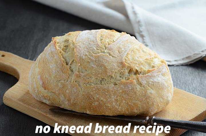 No Knead Bread Loaf on Cutting Board with a Buttered Slice of Bread