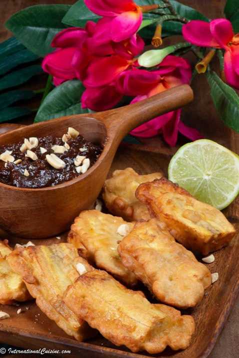 a plateful of battered and fried plantains served with a spicy peanut sauce
