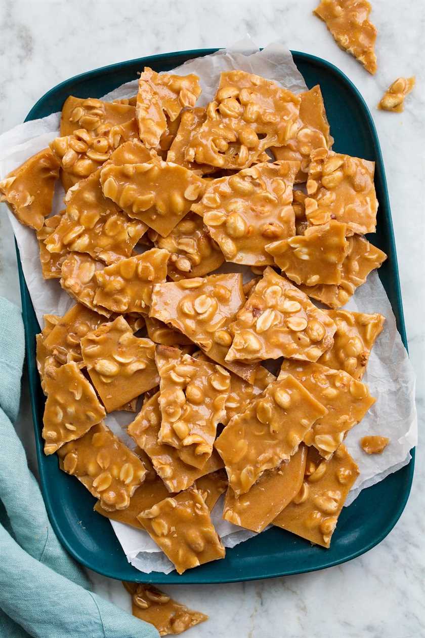Peanut Brittle shown from above on a rectangular blue platter covered with parchment paper.