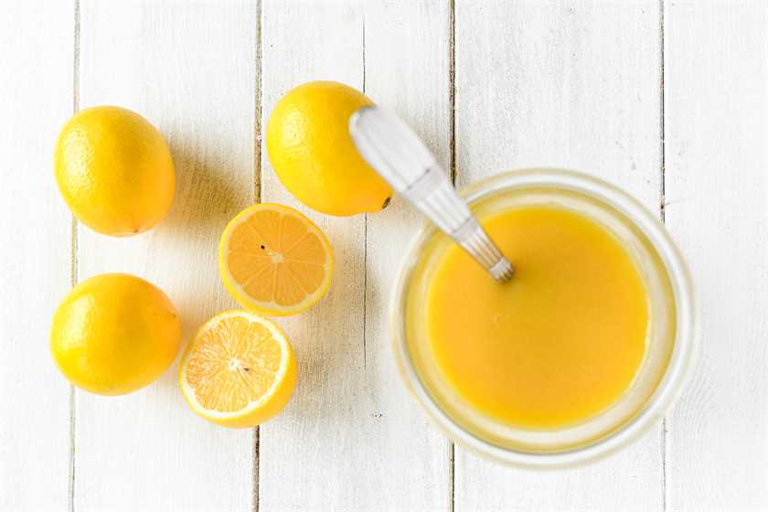 honey Meyer lemon curd in a jar with spoon and lemons