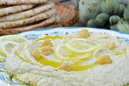 Lemony Artichoke Hummus on a plate garnished with lemon slices and chickpeas.