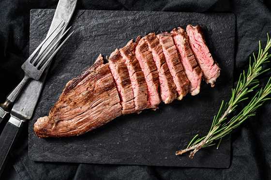 flank steak with rosemary on a black stone board