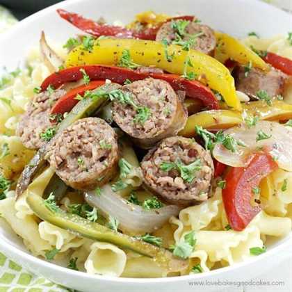 Rustic Italian Sausage with Peppers and Onions in a white bowl close up.