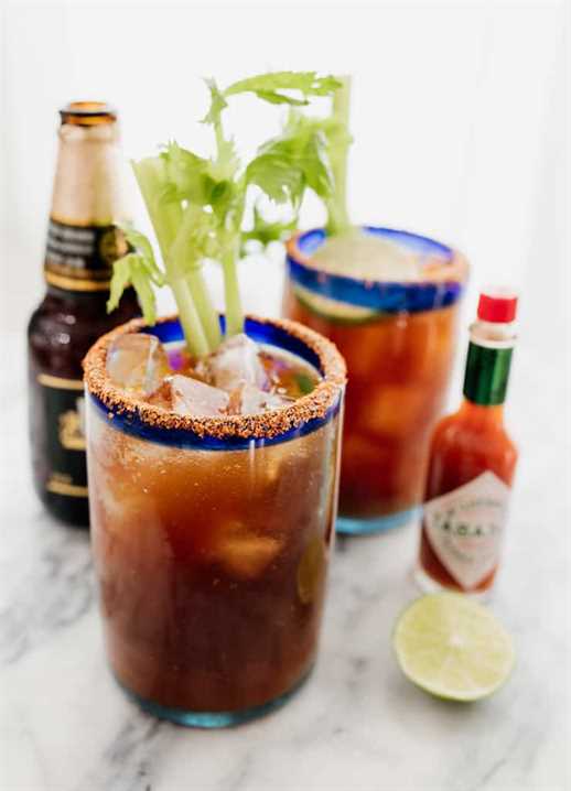 Mexican beer cocktail in two michelada glasses with tabasco and beer on the side