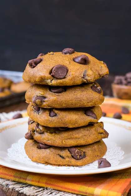 A white plate on an orange towel with a stack of pumpkin chocolate chip cookies
