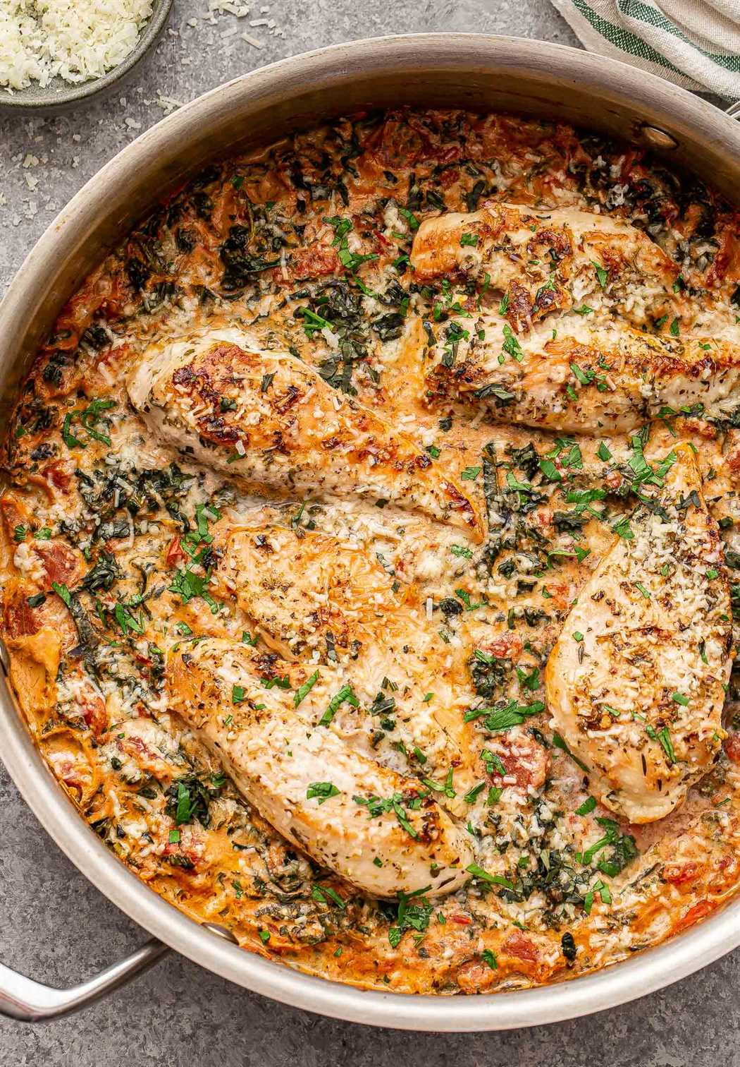 Creamy Italian Chicken in a metal skillet. Topped with parmesan cheese and basil.