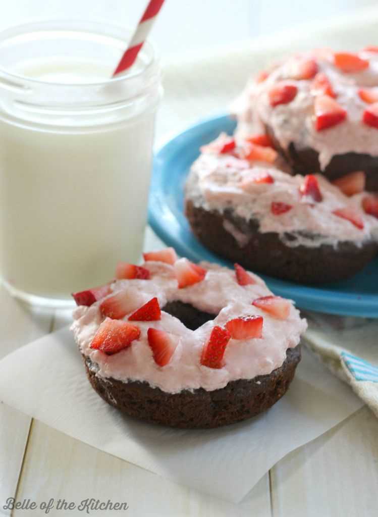 Donuts de chocolate con glaseado de fresa y un vaso de leche.