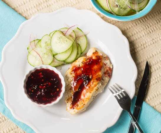 Raspberry-Chipotle Chicken Breasts with Cucumber Salad on a white plate.