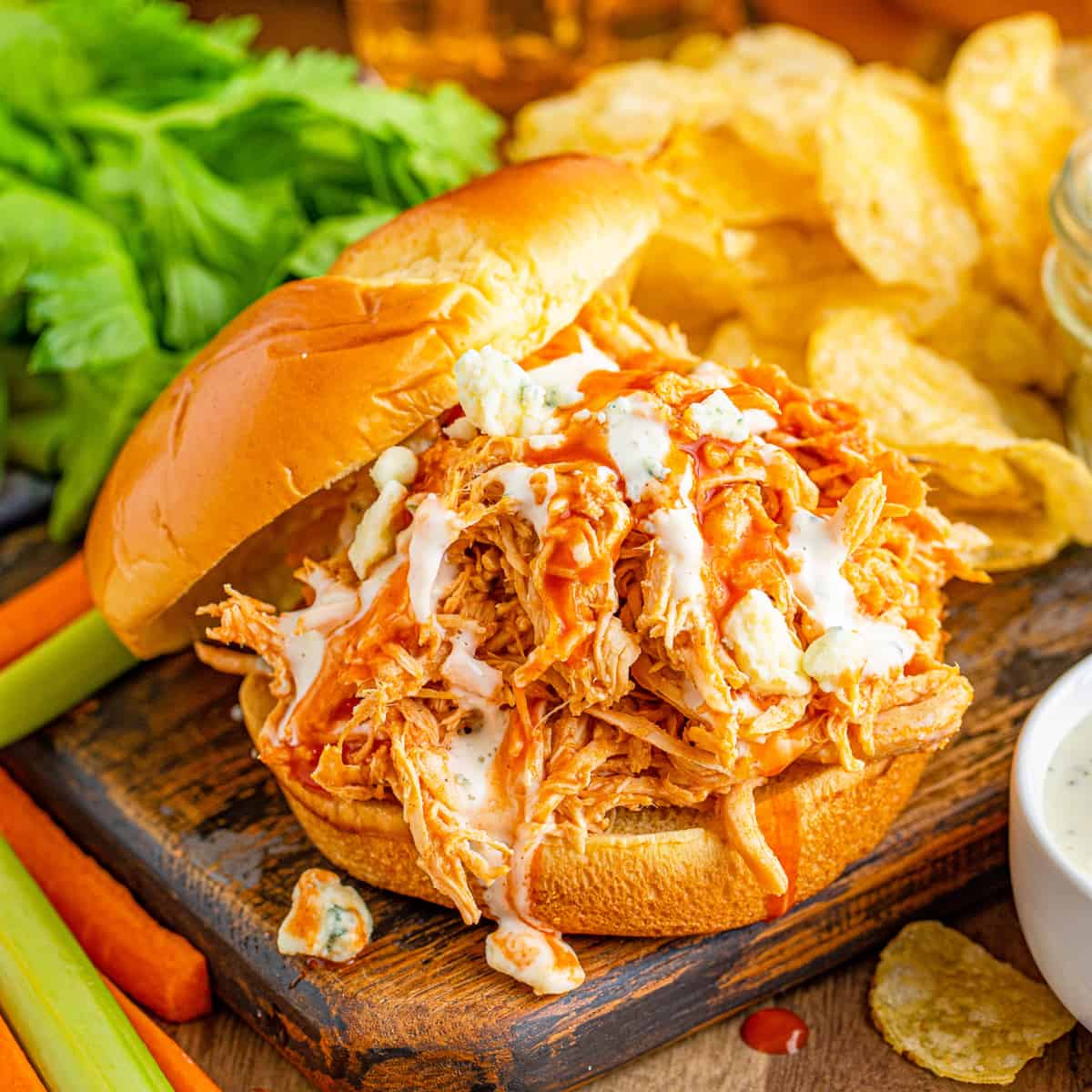 Square image of Buffalo Chicken Sandwiches on bun with hot sauce, ranch and blue cheese