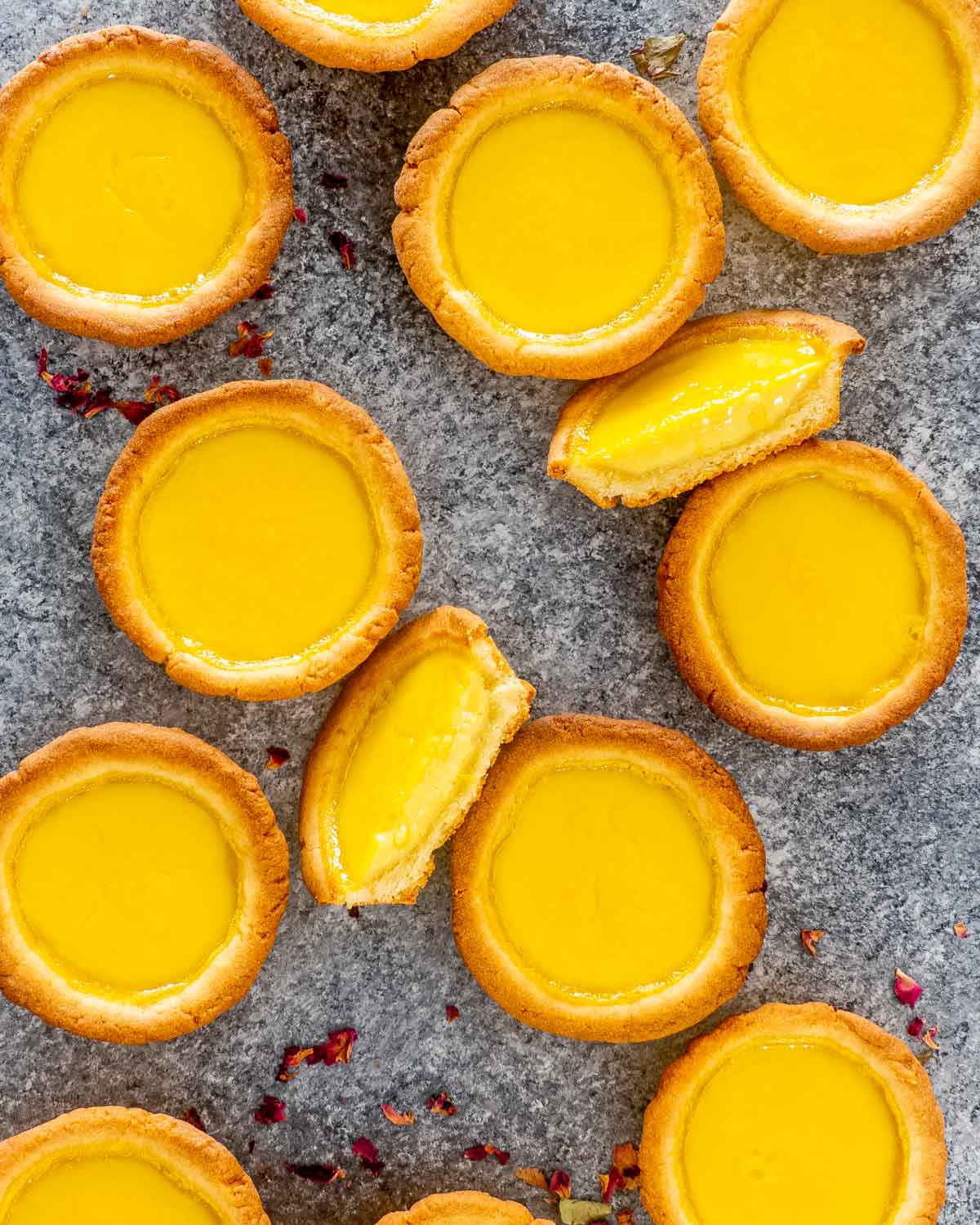 a bunch of egg tarts on a table with one cut in half.