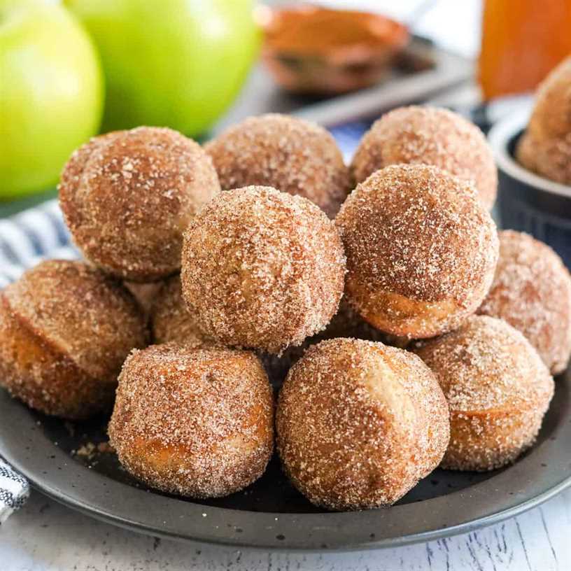 Square image of Apple Cider Donut Holes on black plate stacked.