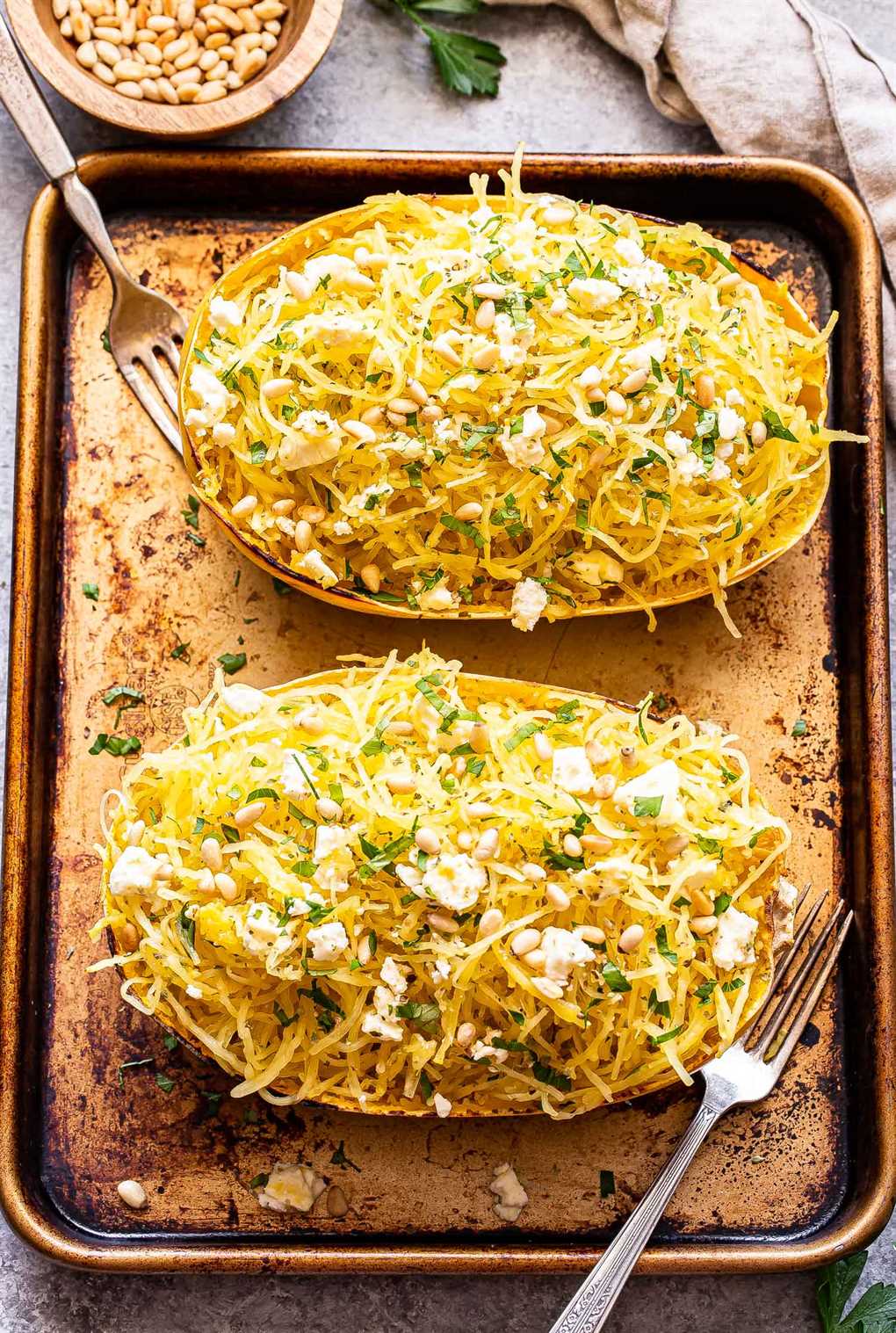 two halves of Spaghetti Squash with Feta and Herbs on a sheet pan with two forks.