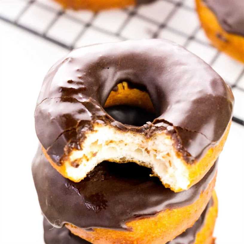 Stack of chocolate glazed biscuit doughnuts with a bite taken out of the top one