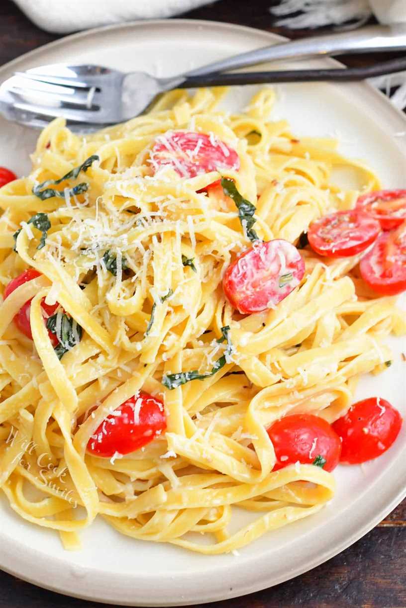 top view of creamy fettuccine on a plate with tomatoes basil and cheese