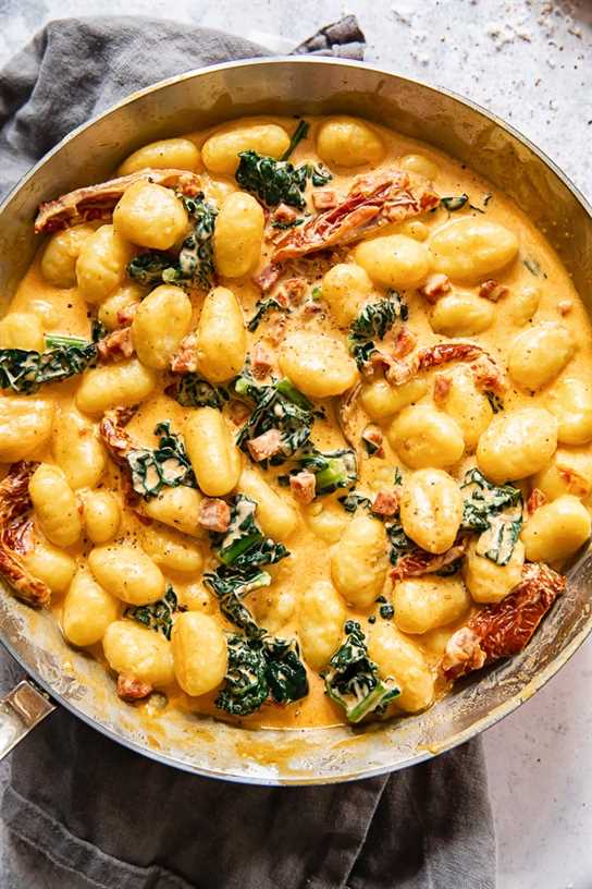 top down view of creamy gnocchi with sun-dried tomatoes and kale in a pan