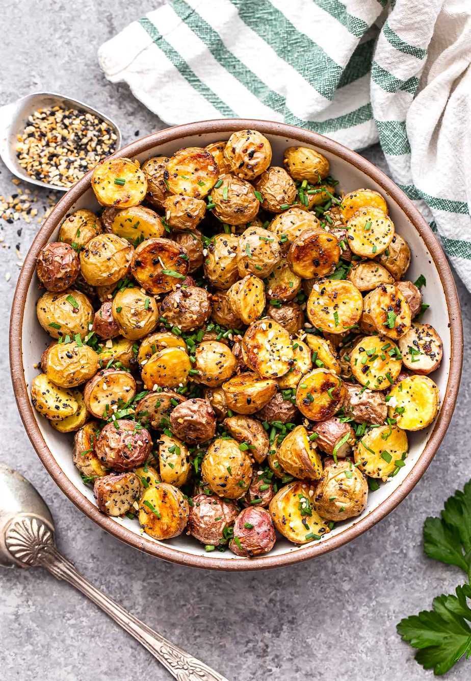 Everything Bagel Roasted Potatoes in a bowl with a spoon of the seasoning behind them.