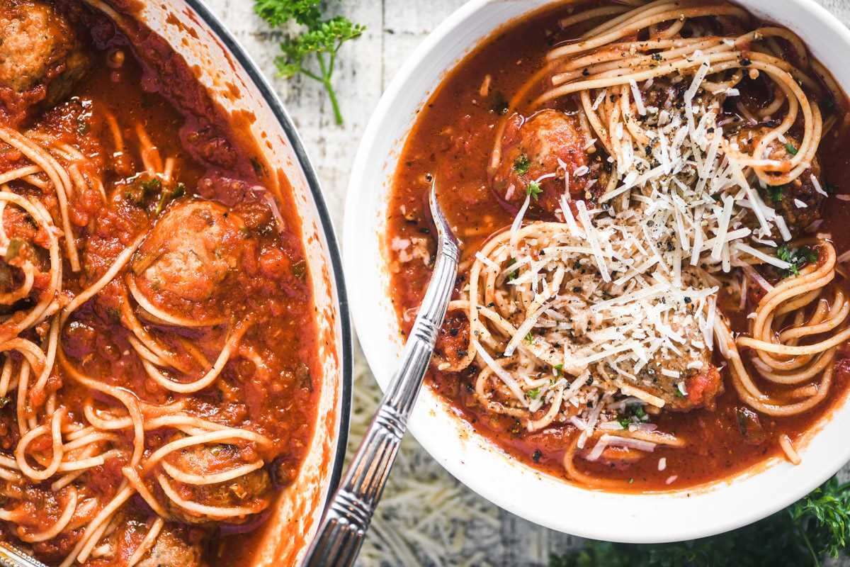 spaghetti and meatball soup in a bowl next to the pot
