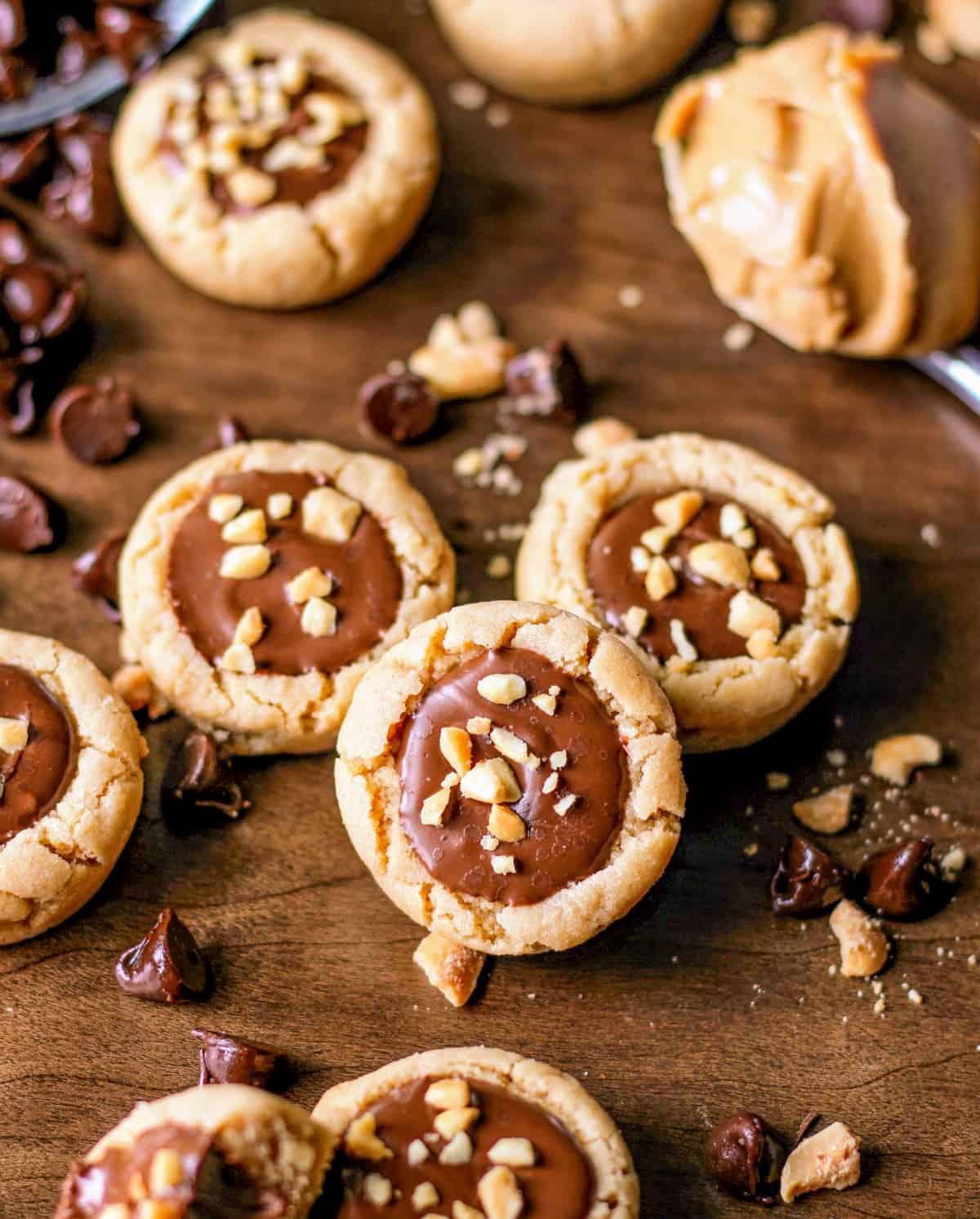 Various Peanut Butter Fudge Cookie Cups with chopped peanuts around them.