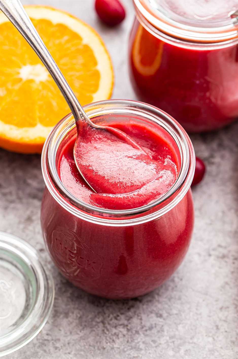 spoon dipping into a jar of cranberry orange curd